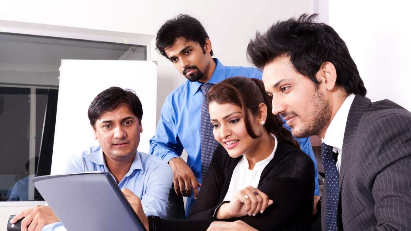 A picture of a workplace where a woman is seen working with three men in the workplace. 