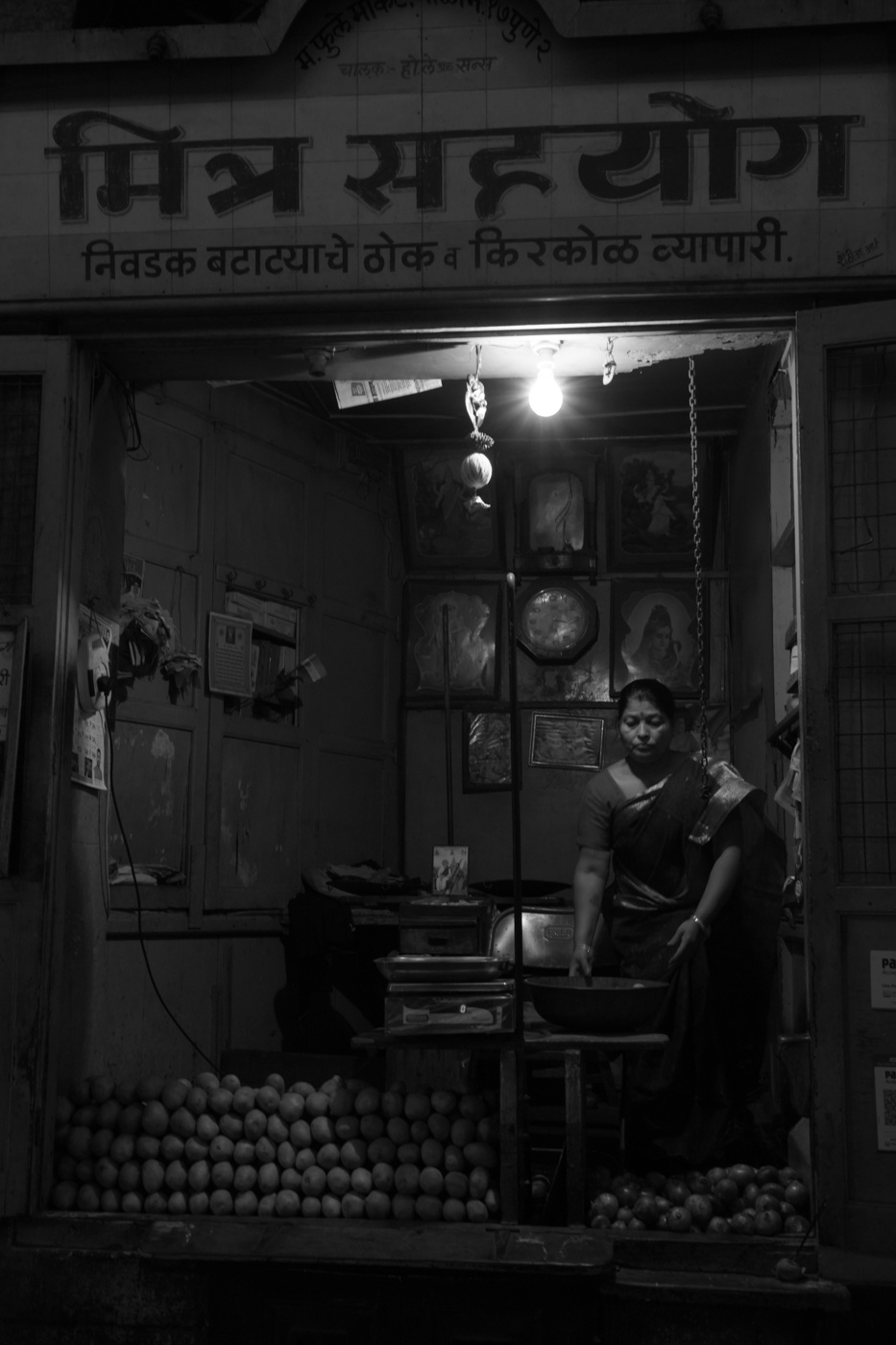 Woman standing in a produce store at night in India.