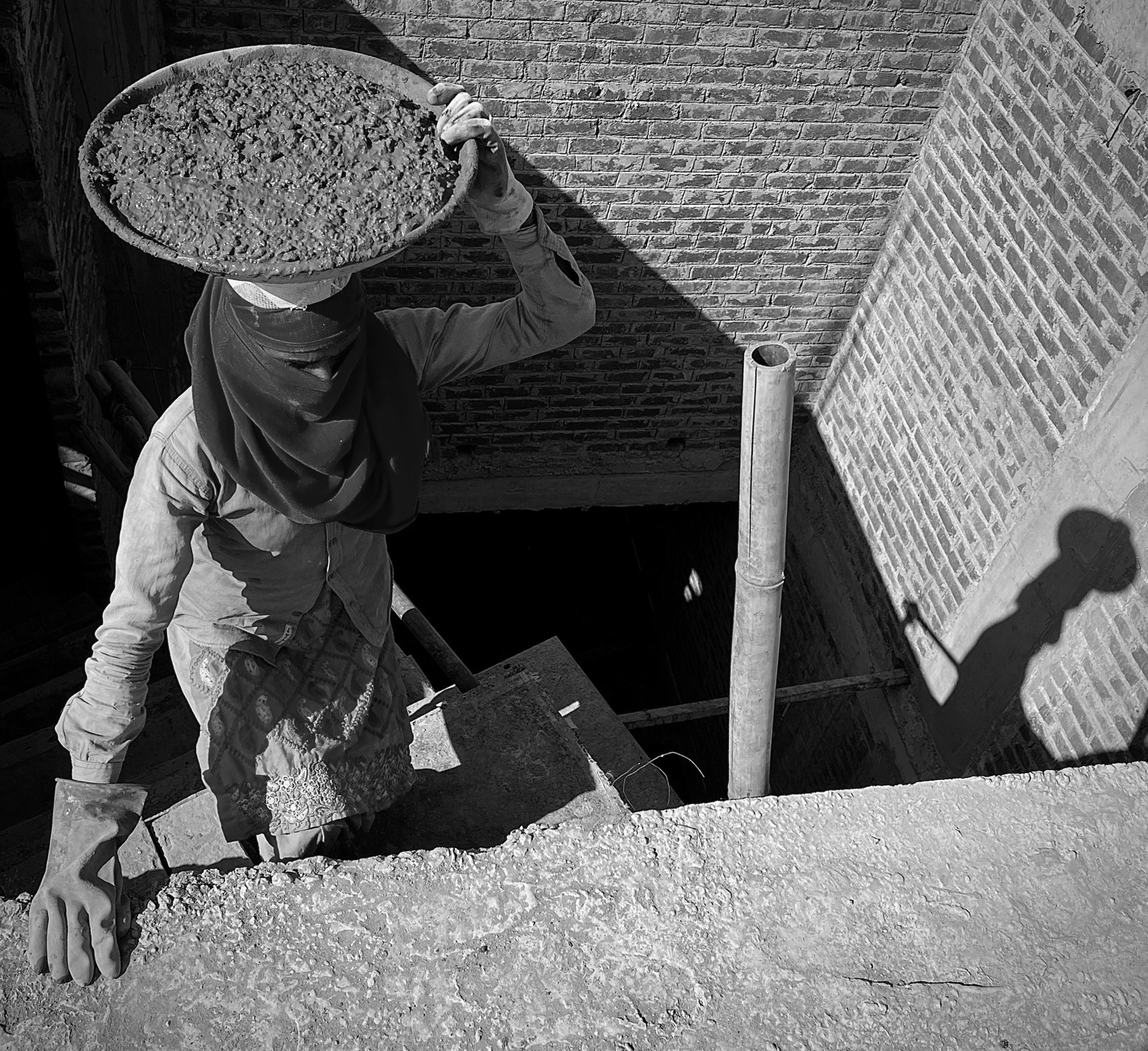 Woman carrying a container of cement at a construction site in Chandigarh.